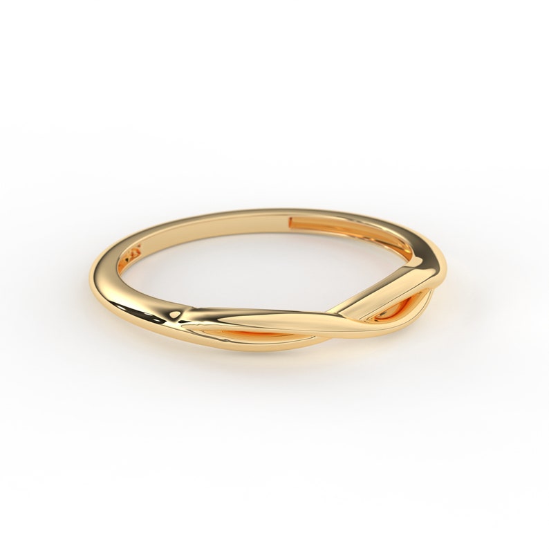 May include: A gold-colored ring with a twisted design. The ring is simple and elegant.