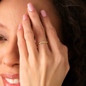 May include: A simple gold band ring with a slightly rounded shape.