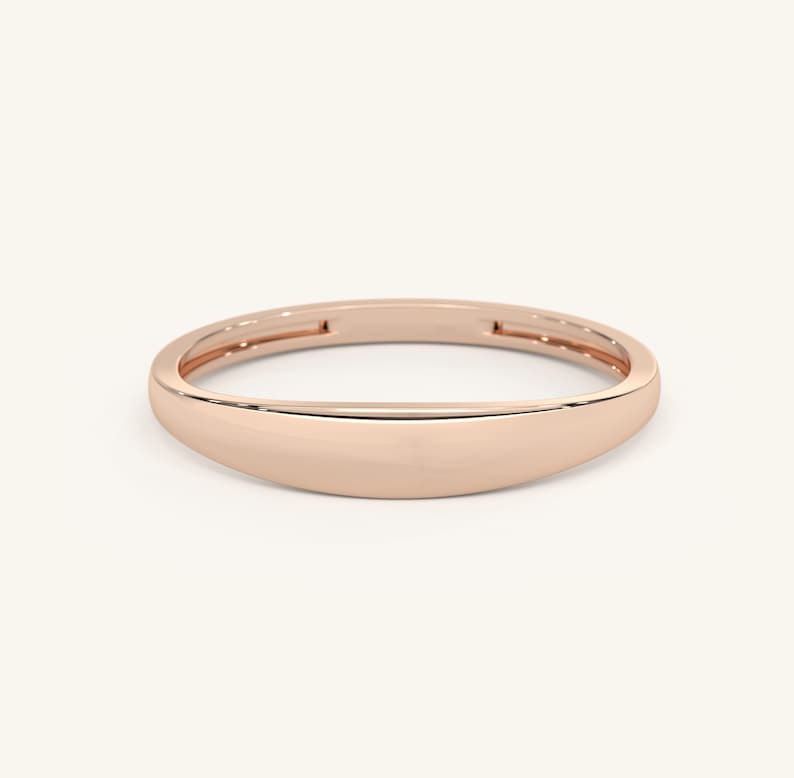 May include: A simple, polished rose gold band ring with a rounded, slightly curved shape.