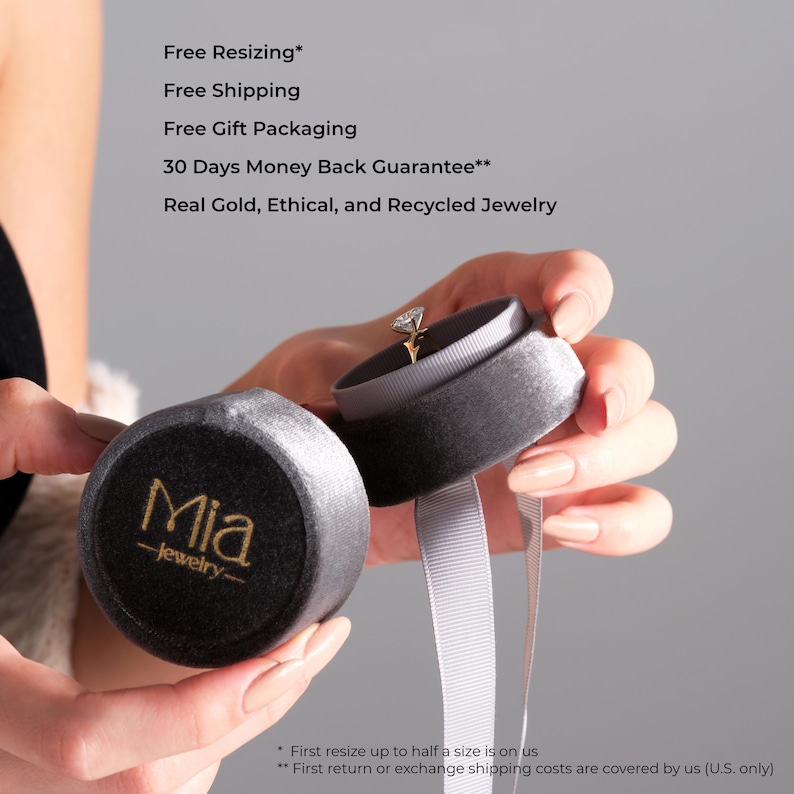 May include: A gold engagement ring with a diamond is displayed in an open gray velvet ring box. The box is held next to a closed matching box with the gold text "Mia -jewelry-". The image also includes the text "Free Resizing", "Free Shipping", "Free Gift Packaging", "30 Days Money Back Guarantee**", and "Real Gold, Ethical, and Recycled Jewelry".