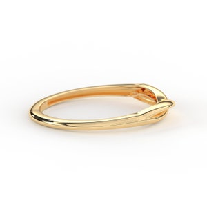May include: A simple gold band ring with a knot design.