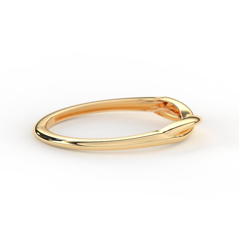 May include: A simple gold band ring with a knot design.