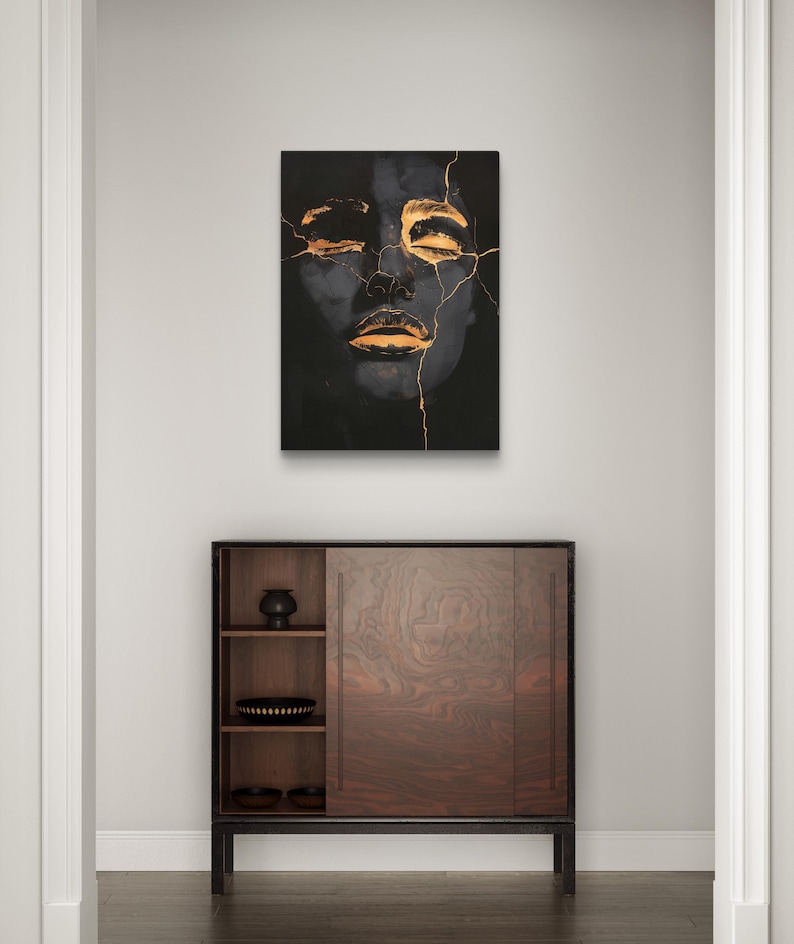 May include: A rectangular wall art print featuring a dark, monochromatic portrait of a face with closed eyes and lips, accented by bright gold-coloured cracks running across the forehead, eyes, and mouth, creating a high-contrast visual effect.