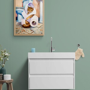 Peut inclure: Une peinture &agrave; l'aquarelle encadr&eacute;e repr&eacute;sente un chat roux en train de jouer avec des rouleaux de papier toilette dans une salle de bain. L'&oelig;uvre comprend des toilettes bleues, des carreaux de sol &agrave; motifs et un cadre en bois brun clair.