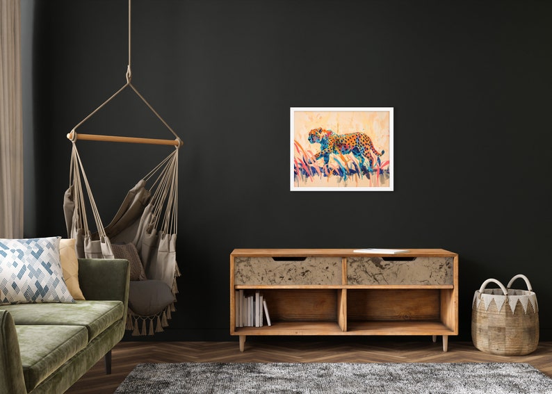 May include: A framed watercolor painting of a leopard in motion. The artwork features a colorful leopard with orange, blue, and yellow spots, set against a backdrop of tall grass. The painting is displayed on a dark wall.