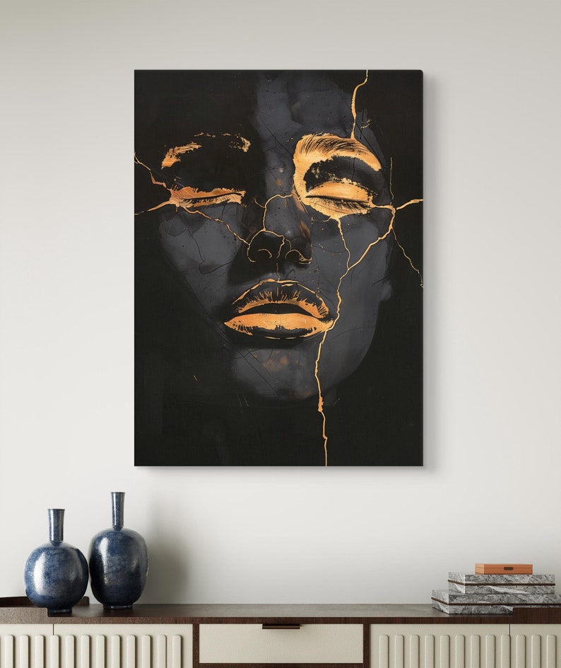 May include: A rectangular wall art print featuring a dark, charcoal-toned face with closed eyes and lips highlighted in metallic gold. The image displays a cracked, kintsugi-inspired aesthetic with thin gold lines running across the facial features.