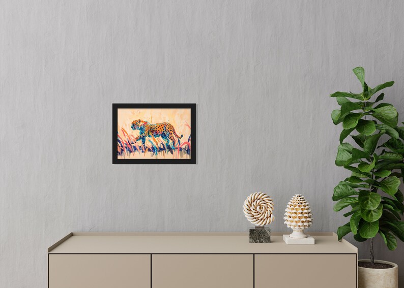 May include: Framed art print featuring a colorful cheetah illustration. The cheetah is depicted in a running pose with a spotted coat, set against a backdrop of tall grass. The artwork is framed in a black border.