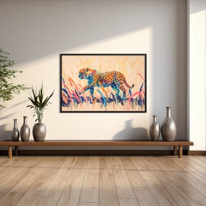 May include: A framed watercolor painting of a cheetah walking through tall grass. The cheetah has orange and black spots, with blue and orange accents. The background is a soft, warm color, and the grass is a mix of blue, pink, and orange.