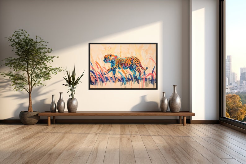 May include: A framed watercolor painting of a cheetah walking through tall grass. The cheetah has orange and black spots, with blue and orange accents. The background is a soft, warm color, and the grass is a mix of blue, pink, and orange.