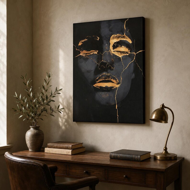 May include: A rectangular wall art canvas featuring a dark, shadowy face with closed eyes and lips highlighted in metallic gold. Thin, jagged gold lines resembling cracks run across the face, contrasting against the deep black background.