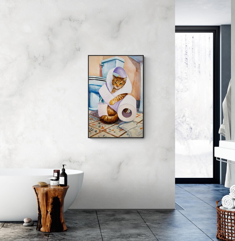 Peut inclure: Peinture &agrave; l'aquarelle d'un chat tigr&eacute; orange et marron envelopp&eacute; dans du papier toilette dans une salle de bain. Un rouleau de papier toilette blanc et des toilettes bleues sont &eacute;galement visibles. L'&oelig;uvre est encadr&eacute;e.