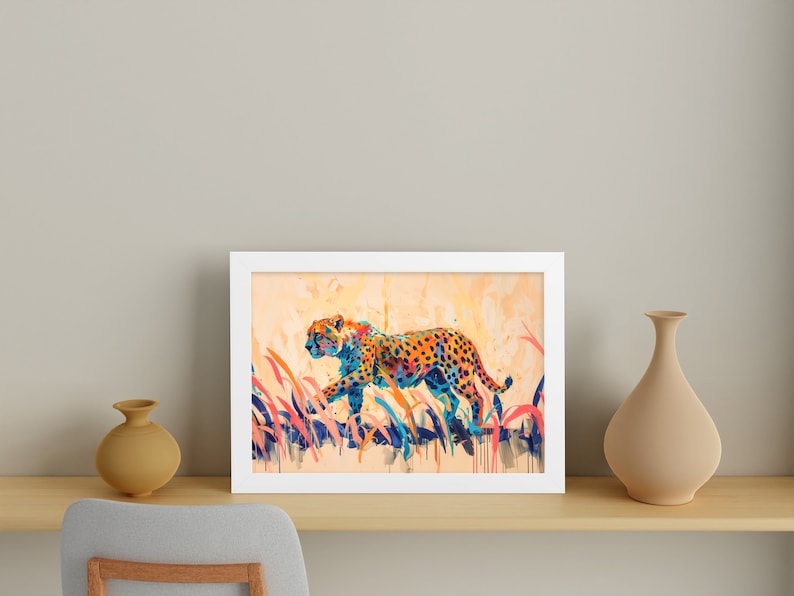 May include: A framed art print featuring a colorful watercolor painting of a cheetah walking through tall grass. The cheetah has orange and black spots with blue and yellow accents. The artwork is in a white frame.