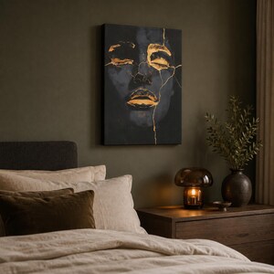 May include: A rectangular canvas wall art piece featuring a dark, moody portrait of a face with closed eyes and lips highlighted in metallic gold paint. The image includes thin, branching gold lines that resemble cracks across the facial features.