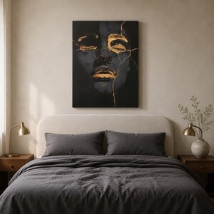 May include: A rectangular wall art canvas featuring a dark, shadowy portrait of a face with closed eyes and lips highlighted in metallic gold. Thin, jagged gold lines resembling cracks run across the forehead, eyes, and nose of the dark figure.