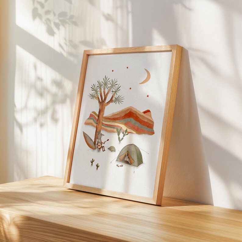 May include: A framed illustration of a desert landscape with a Joshua tree, mountains, a crescent moon, and stars. A fox is playing a banjo, a turtle is sitting nearby, and a green tent is set up in the scene.
