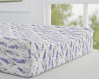 May include: White fitted cot sheet with a lavender floral pattern. The sheet has a subtle watercolour effect and features purple lavender flowers and green stems on a white background.