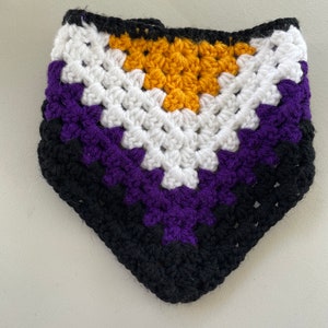 May include: A crocheted triangular scarf in black, purple, white, and yellow. The colors are arranged in a pattern that resembles the non-binary pride flag.