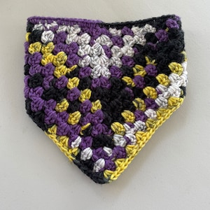 May include: A crocheted triangle scarf in black, purple, yellow, and white.