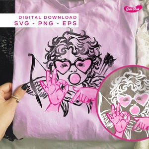 May include: A pale pink t-shirt with a graphic of Cupid wearing heart-shaped glasses and blowing a bubble. The Cupid illustration is in black and pink, holding a bow and arrows. Text at the top reads "DIGITAL DOWNLOAD SVG - PNG - EPS".