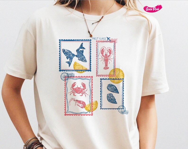 Pode incluir: Camiseta creme com quatro desenhos de selos postais com ilustra&ccedil;&otilde;es de frutos do mar. Os selos retratam peixes, uma lagosta, um caranguejo com camar&otilde;es e ostras. Cada selo &eacute; emoldurado em azul ou rosa com o texto First Class.