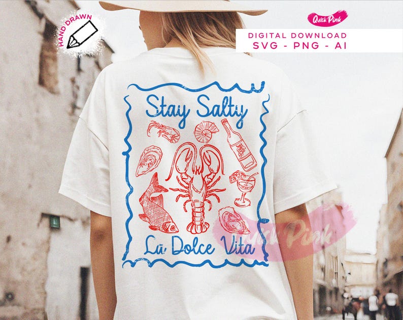 以下が含まれることがあります： 「Stay Salty La Dolce Vita」と書かれた青と赤のグラフィックデザインが施された白いTシャツ。グラフィックには、ロブスター、魚、ワインボトル、その他のシーフードのイメージが含まれています。