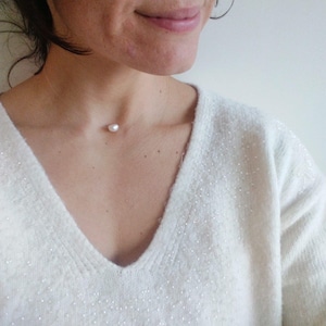 May include: A simple white pearl necklace on a woman's neck. The necklace is delicate and features a single pearl pendant.