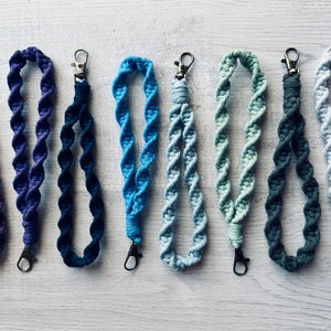 May include: Six colorful crocheted lanyards with metal clasps. The lanyards are in shades of blue, green, and purple.