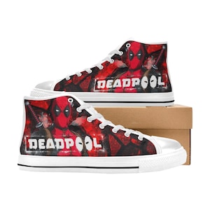May include: White high-top canvas shoes with a red, black, and white graphic print of Deadpool. The shoes have white laces and a white rubber sole. The graphic print features Deadpool's face and the word "DEADPOOL" in white letters.