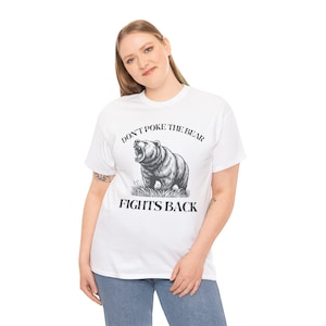 May include: White t-shirt featuring a black and white illustration of a bear with the text "DON'T POKE THE BEAR" above the bear and "FIGHTS BACK" below. The bear is roaring with its mouth open.