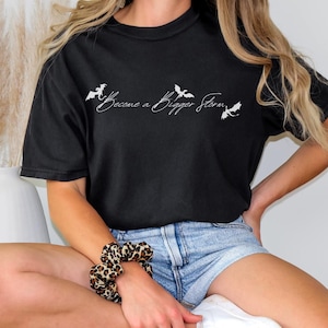 May include: Black t-shirt with white bats and the text "Become a Bigger Storm".