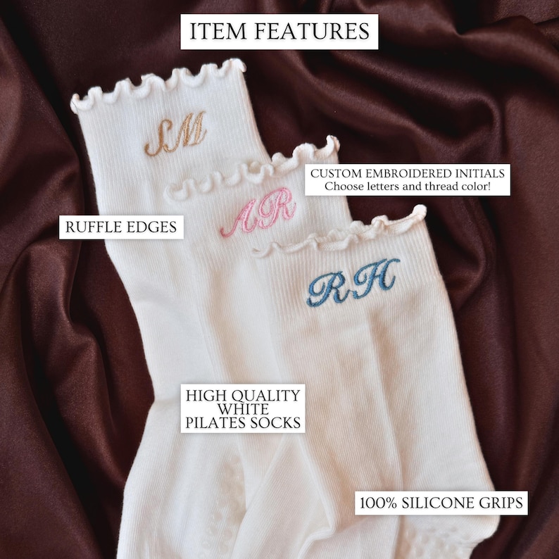 Custom monogram pilates socks photographed on rich satin fabric featuring delicate embroidered initials in soft pink blue and neutral thread colors on white ruffle socks designed for pilates class barre workouts yoga studio outfits and trendy clean girl aesthetic fashion perfect for bridesmaid proposal boxes bachelorette party gifts matching friend accessories travel essentials cozy self care gift baskets and personalized gifts for women who love elegant minimalist embroidered accessories