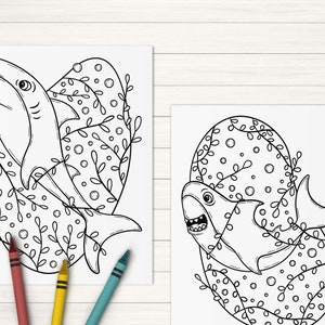 May include: Two black and white line drawings of sharks in a circular frame with a floral design. The sharks are swimming in the frame with their mouths open.