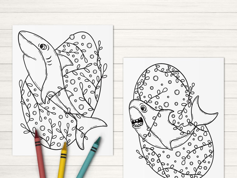 May include: Two black and white line drawings of sharks in a circular frame with a floral design. The sharks are swimming in the frame with their mouths open.