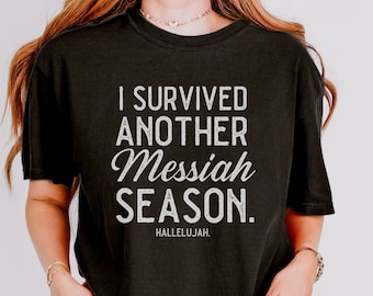 May include: A black t-shirt with the text "I survived another Messiah season. Hallelujah." printed in white.