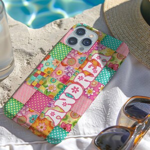 May include: A colorful patchwork phone case with the word "Summer" in white script. The case features a mix of floral, polka dot, and plaid patterns in pink, green, and yellow. Sunglasses and a straw hat are nearby.