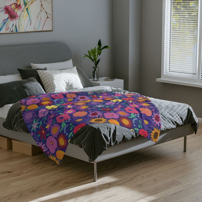 May include: A bed with a floral patterned duvet cover. The duvet cover features a variety of colorful flowers, including pink, yellow, orange, and red. The bed is made with a dark gray comforter and pillows.