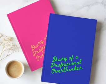 May include: Two hardcover journals, one bright pink and one royal blue, both featuring the text Diary of a Professional Overthinker in cursive script. The pink journal has yellow text, while the blue journal has bright green text.