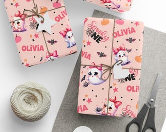 Può includere: Carta da regalo rosa chiaro con un motivo ripetuto di fantasmi dei cartoni animati con fiocchi rosa, zucche arancioni, ragni neri, ragnatele, stelle e il testo Spooky One e Olivia, legata con spago ed etichette a forma di stella.