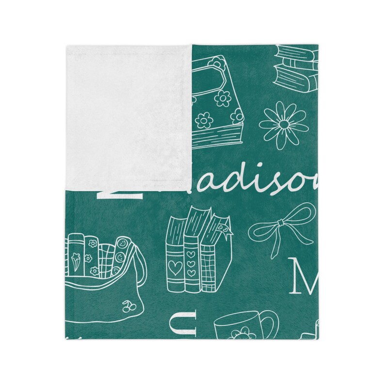 May include: Teal blue fleece blanket with a white design of books, flowers, and the word "madison".