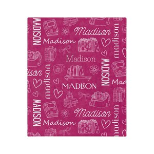 May include: A pink fabric with a white repeating pattern of books, hearts, flowers, and the name "Madison".