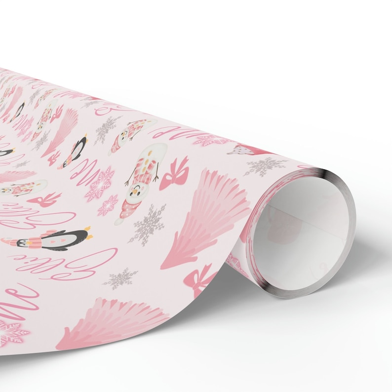 May include: Pink wrapping paper with a winter theme featuring penguins, snowmen, and snowflakes. The paper also has the words "Let it snow" written in pink cursive.