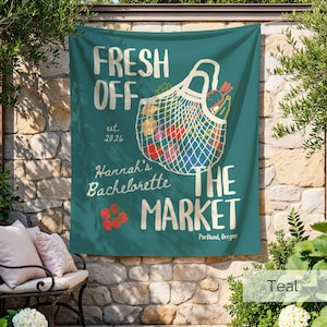 Peut inclure: Une banni&egrave;re en tissu sarcelle avec le texte FRESH OFF THE MARKET, est. 2026, Hannah's Bachelorette et Portland, Oregon. Le motif comprend un sac filet blanc rempli de produits color&eacute;s et une petite grappe de tomates rouges.