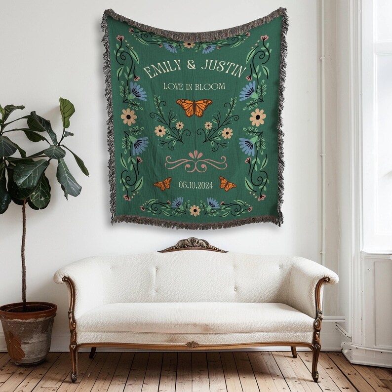 May include: A green tapestry with a floral design and butterflies. The tapestry has the text "Emily & Justin Love in Bloom 05.10.2024" in white.