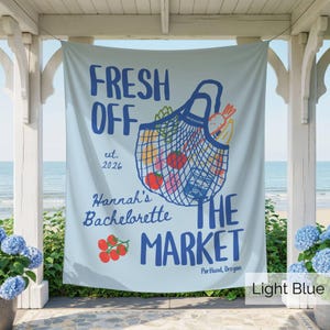 Peut inclure: Une banni&egrave;re en tissu bleu clair avec un sac de march&eacute; en filet bleu fonc&eacute; rempli d'illustrations de produits frais. Le texte indique FRESH OFF THE MARKET, est. 2026, Hannah's Bachelorette, et Portland, Oregon, avec des tomates rouges.