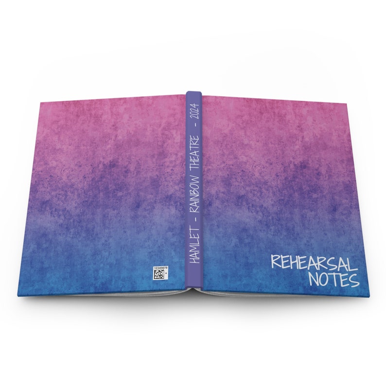 K&ouml;nnte beinhalten: Ein geschlossenes Buch mit einem blauen und rosa Ombre-Umschlag. Der Buchr&uuml;cken tr&auml;gt den Text "HAMLET - RAINBOW THEATRE - 2024". Der Einband hat den Text "REHEARSAL NOTES" in Wei&szlig;.