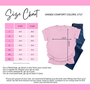 May include: Unisex t-shirt size chart with measurements in inches for sizes S through 4XL. The chart shows width and length measurements for each size. The image also shows a pink t-shirt with a white chest measurement line and a white length measurement line.