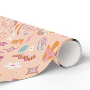May include: Peach-colored wrapping paper with a retro-inspired pattern featuring rainbows, mushrooms, stars, and the word "OUTER" in a groovy font.