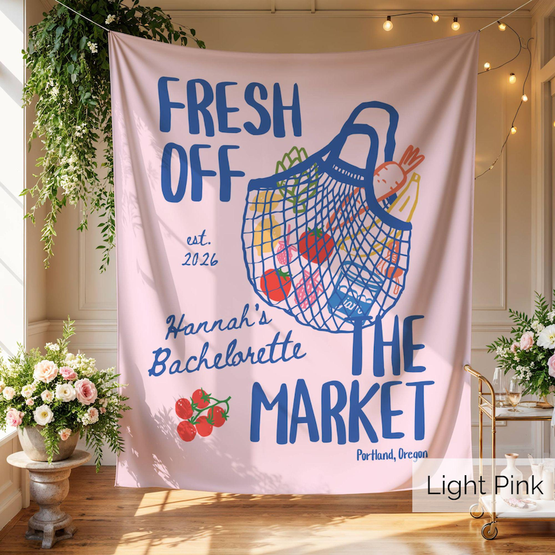 Peut inclure: Une tapisserie murale rose clair avec un graphique bleu repr&eacute;sentant un sac de courses en filet rempli de produits. Le texte indique : FRESH OFF THE MARKET, est. 2026, Hannah's Bachelorette, et Portland, Oregon. Inclut des tomates et une carotte.