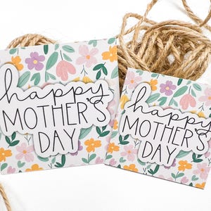 May include: Two white cards with a floral pattern and the text "happy mother's day" in black script.