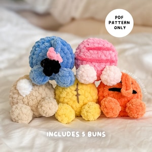 Puede incluir: Cinco personajes amigurumi de panecillos tejidos a crochet en varios colores, incluyendo azul, rosa, beige, amarillo y naranja. El texto "PDF PATTERN ONLY" e "INCLUDES 5 BUNS" es visible en la imagen.
